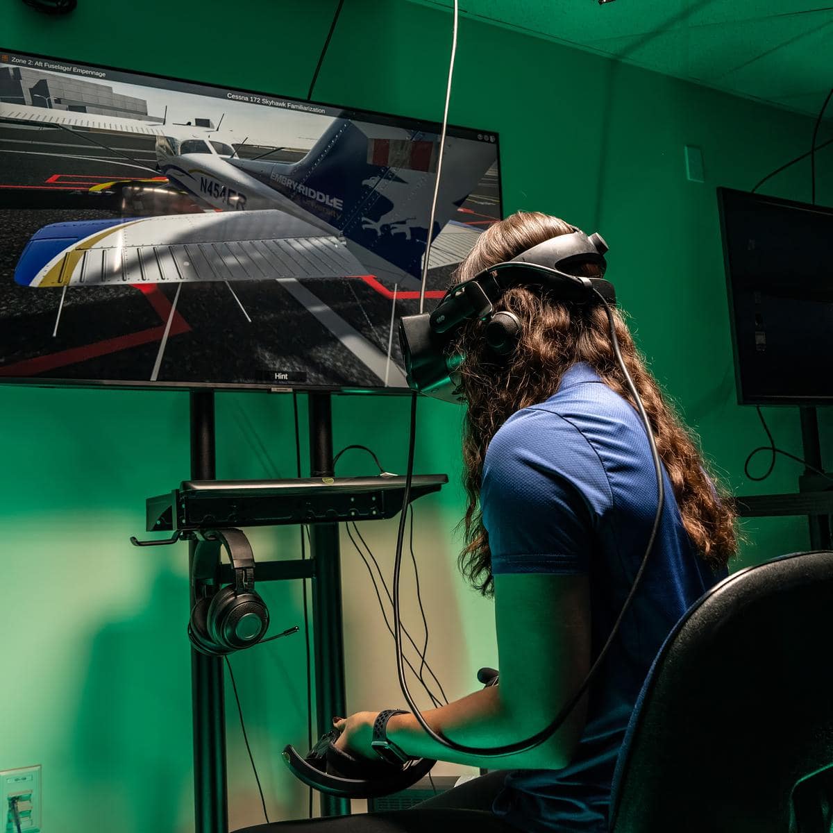 Student in headset with screen showing three-dimensional model of Cessna 172.