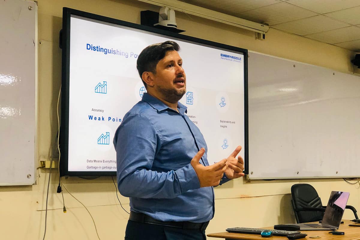 Dr. Burak Cankaya lectures in front of white board.