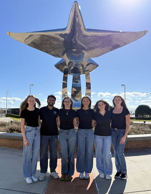 Students pose in front of the flight statue at the Daytona Beach Campus.
