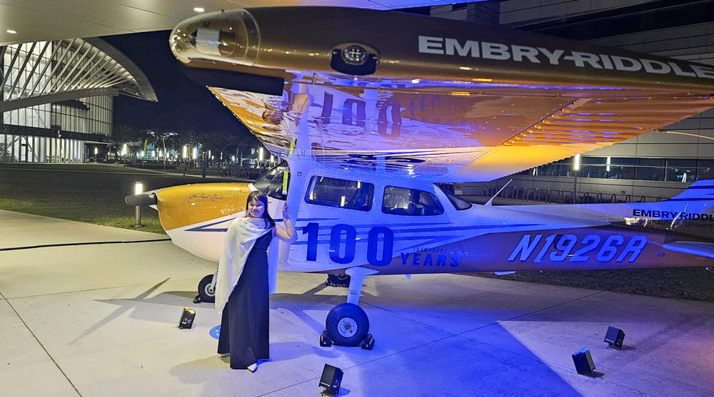 Woman stands in front of the Embry-Riddle Centennial plane.