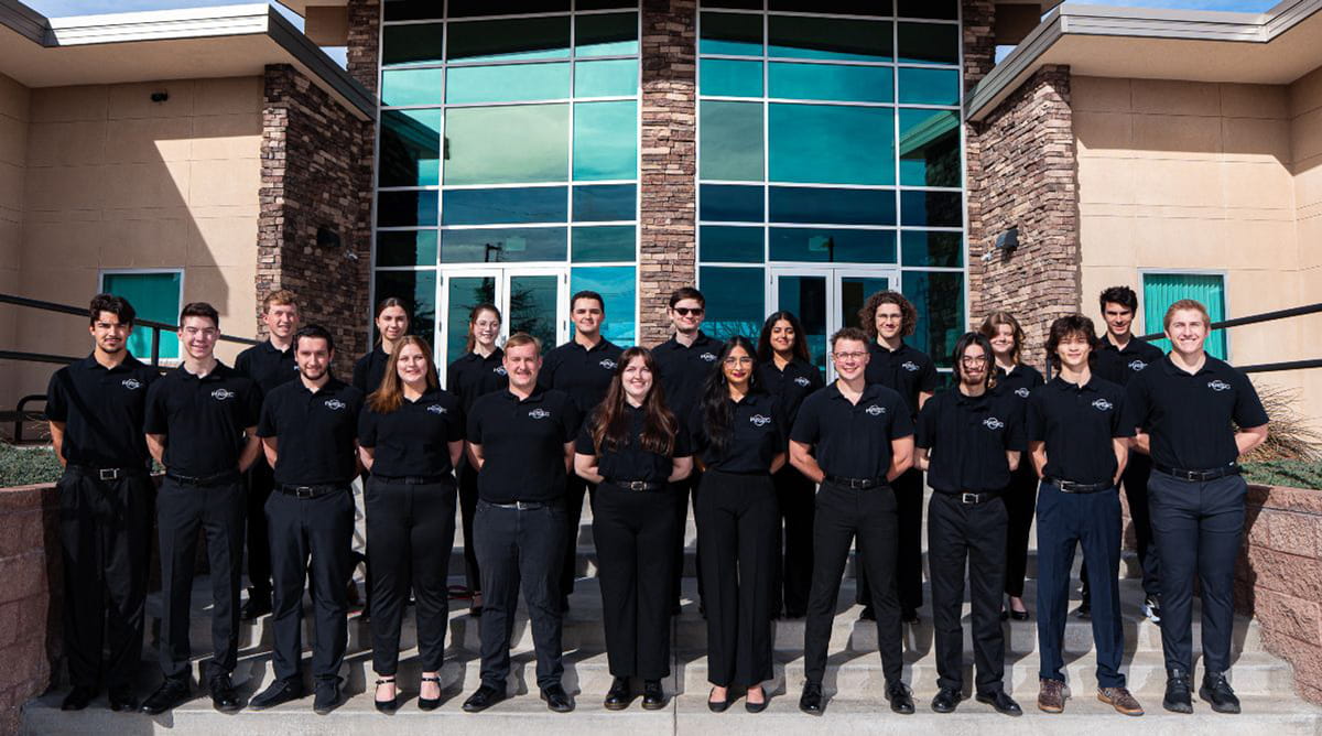 A group of students pose in front of the Prescott Campus.