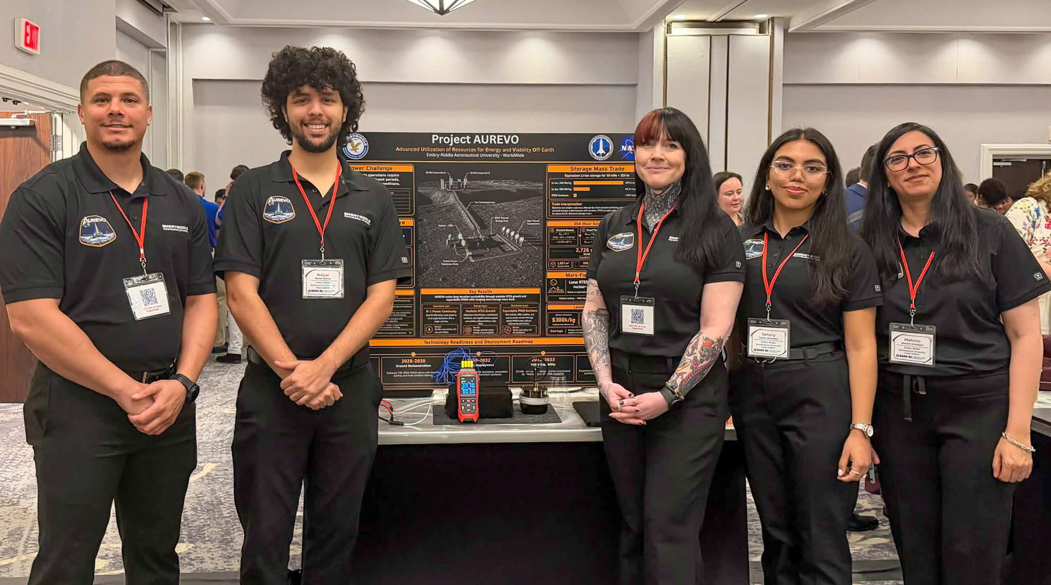 The Embry-Riddle Worldwide team stand in front of the poster describing their lunar energy system. From left, students Carlon Oliver, Naiyar Shaman, Kelly McElwain, Sahory Benavides Villareal and Mahroo Hamedani. 