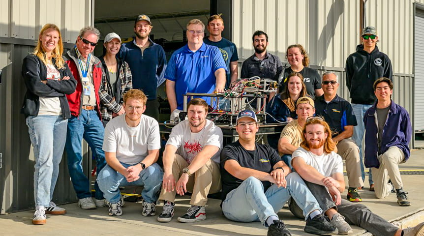 Team stands in front of a hangar 