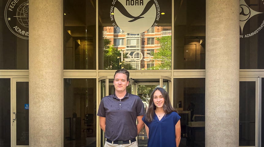 man and woman stand in front of columned building that is NOAA headquarters