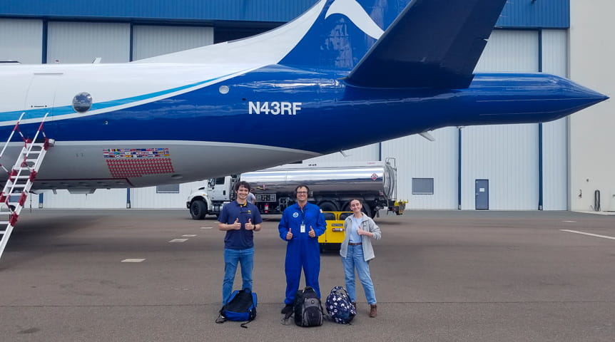Three people in front of NOAA's hurricane hunter aircraft