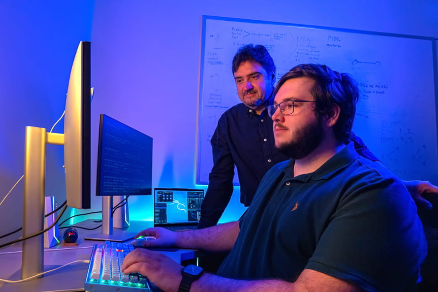 Two men stare at a computer screen