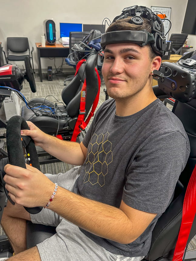 Man hold steering wheel of a simulator with electrodes on his head