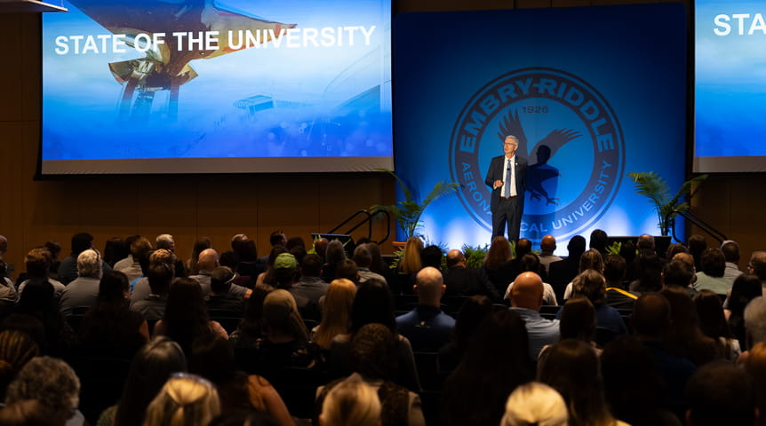 Embry-Riddle President P. Barry Butler presents his State of the University address on a stage in a packed auditorium