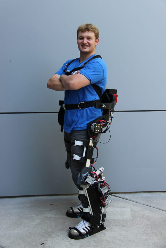 Man stands with exoskeleton device wrapped around his legs