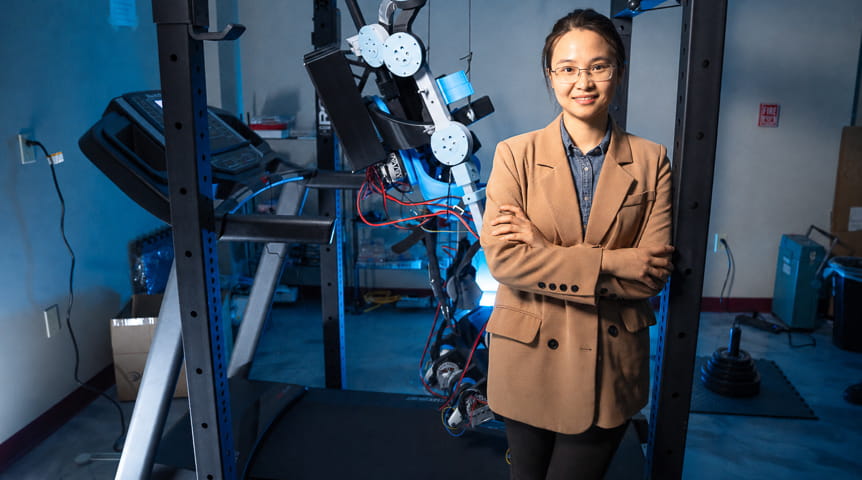 woman stands in front of exoskeleton device