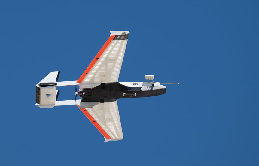 Small white and red aircraft with propeller flying against clear blue sky
