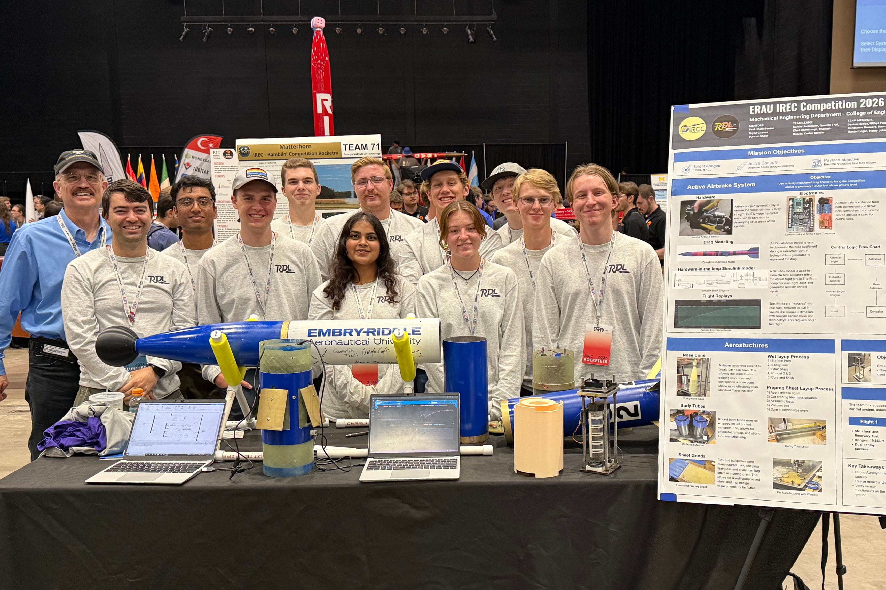 Embry-Riddle’s Rocket Development Laboratory (RDL) team representatives pose with their IREC 2026 rocket and project display. From left: Professor Mark Benton, Bryce Chanes, Dhanush Balusa, Calvin Lindemann, Hunter Logan, Keenan Walsh, Chad Alumbaugh, Nithya Pattamatta, Daxton Hedge, Constance Brainerd, Quentin Trull and Henry Johnson.