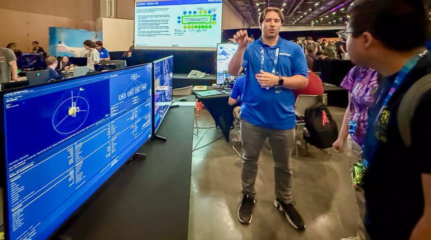 A man explains a screen that shows the OrbitVE space digital twin environment 