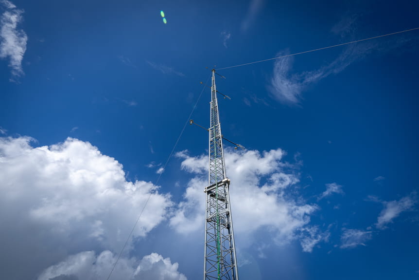 Tall metal communication tower stretching toward blue sky with white clouds