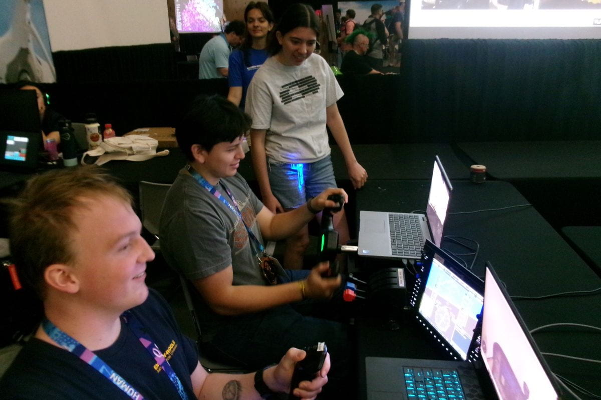Prescott Campus students Kalen Hazlet and Aaron Ybarra-Rojas demonstrate flight simulators during the Aerospace Village capture-the-flag (CTF) challenge at DEF CON 34 while fellow students Sophia Eads and Antoinette Hults look on. (Photo: Kyle Wheaton)