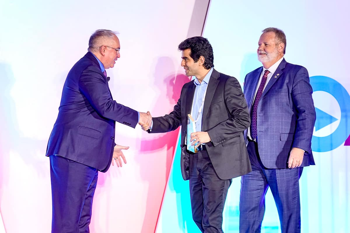 Man shakes hand while receiving crystal award