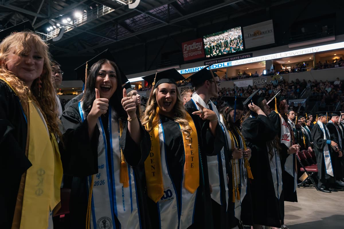 Students in caps and gowns wave excitedly