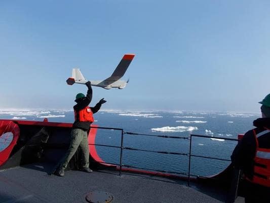National Oceanographic and Atmospheric Administration scientist Kevin Vollbrecht launches a Puma uncrewed aerial vehicle from the bow of the Coast Guard Cutter Healy. (Photo: U.S. Coast Guard)