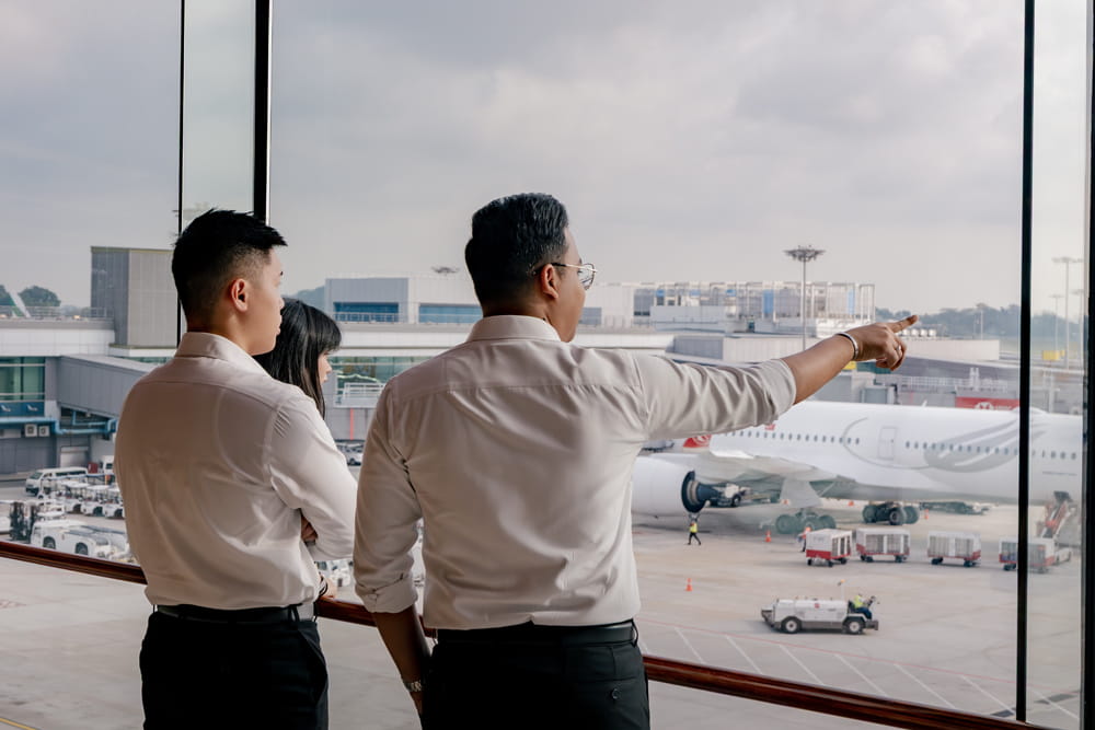 Three Embry-Riddle students stand in an airport overlooking the flight field