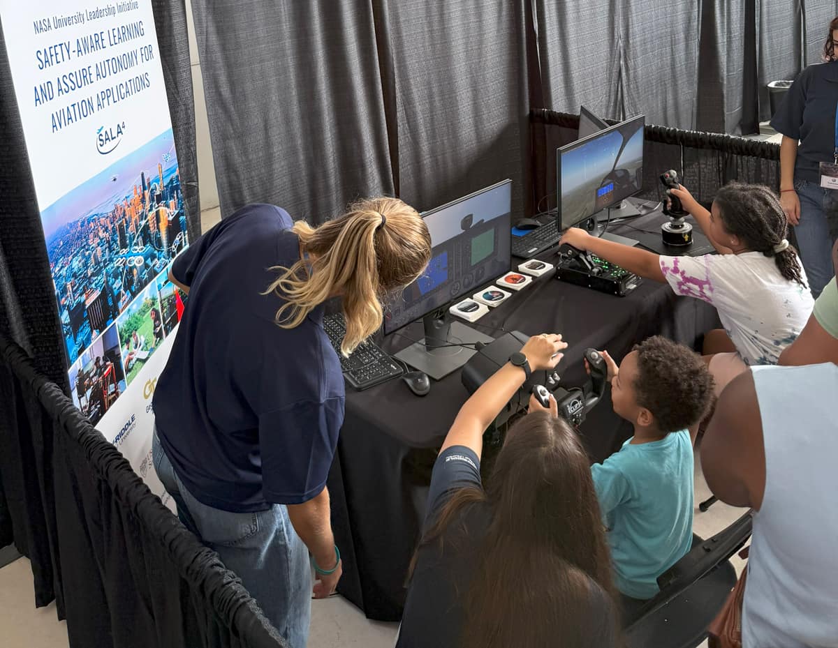 Young students play on a simulator during STEM Outreach