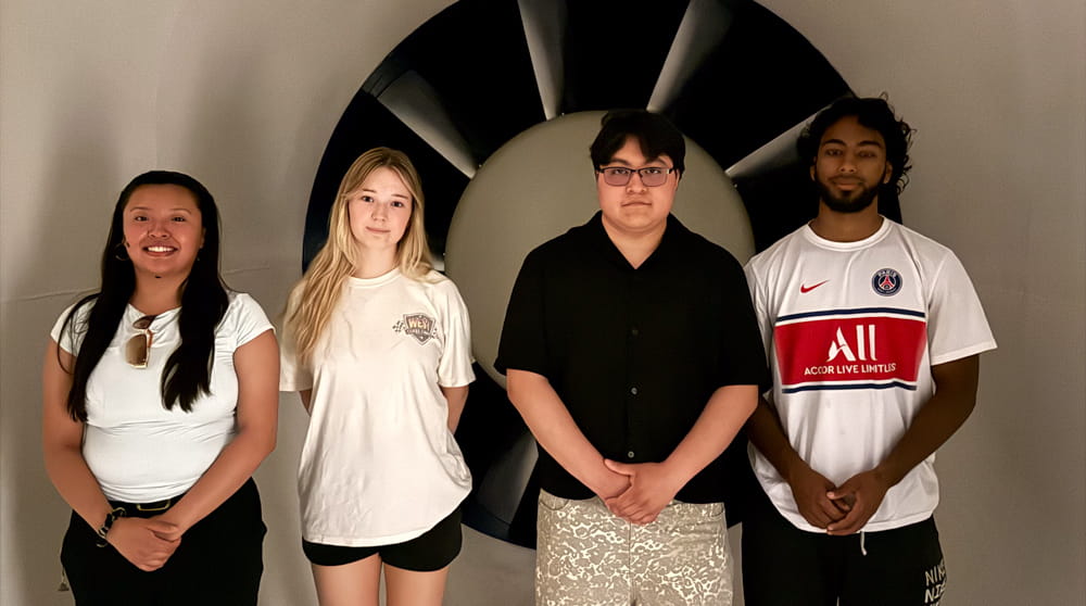 Students pose in front of an engine