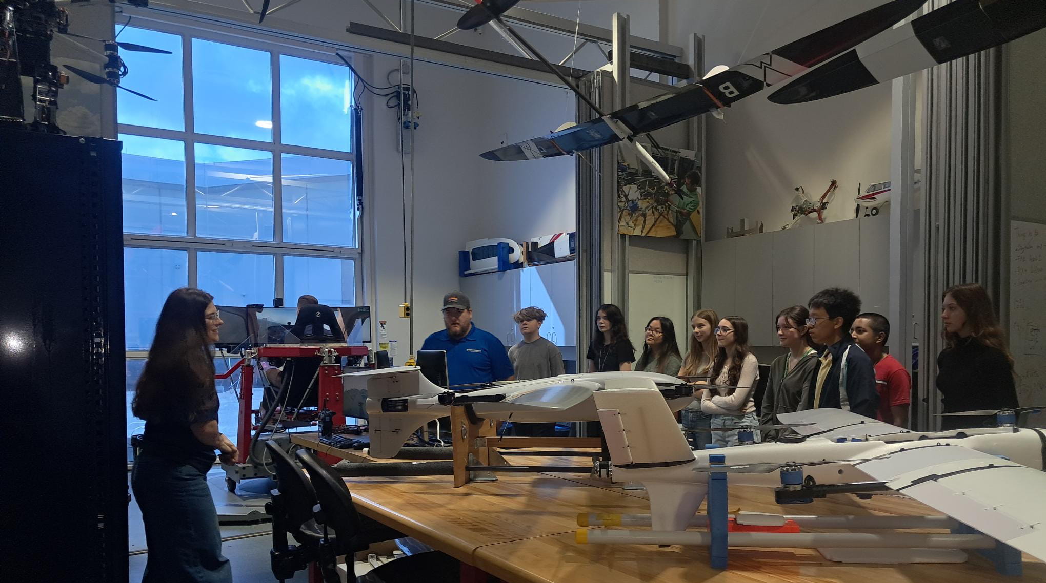 Grade school students look at a drone in a lab.