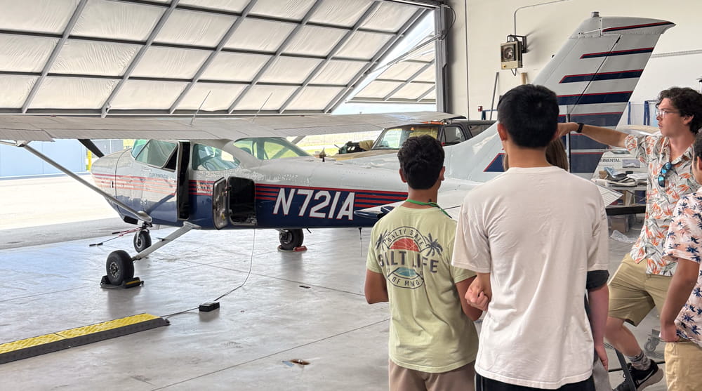 Students look at a plane in a hangar.