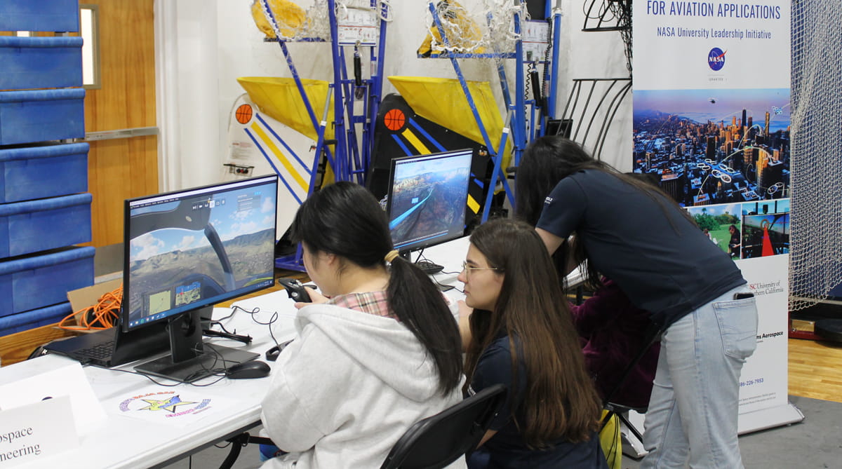 Three students work on a computer that is a UAS Simulator