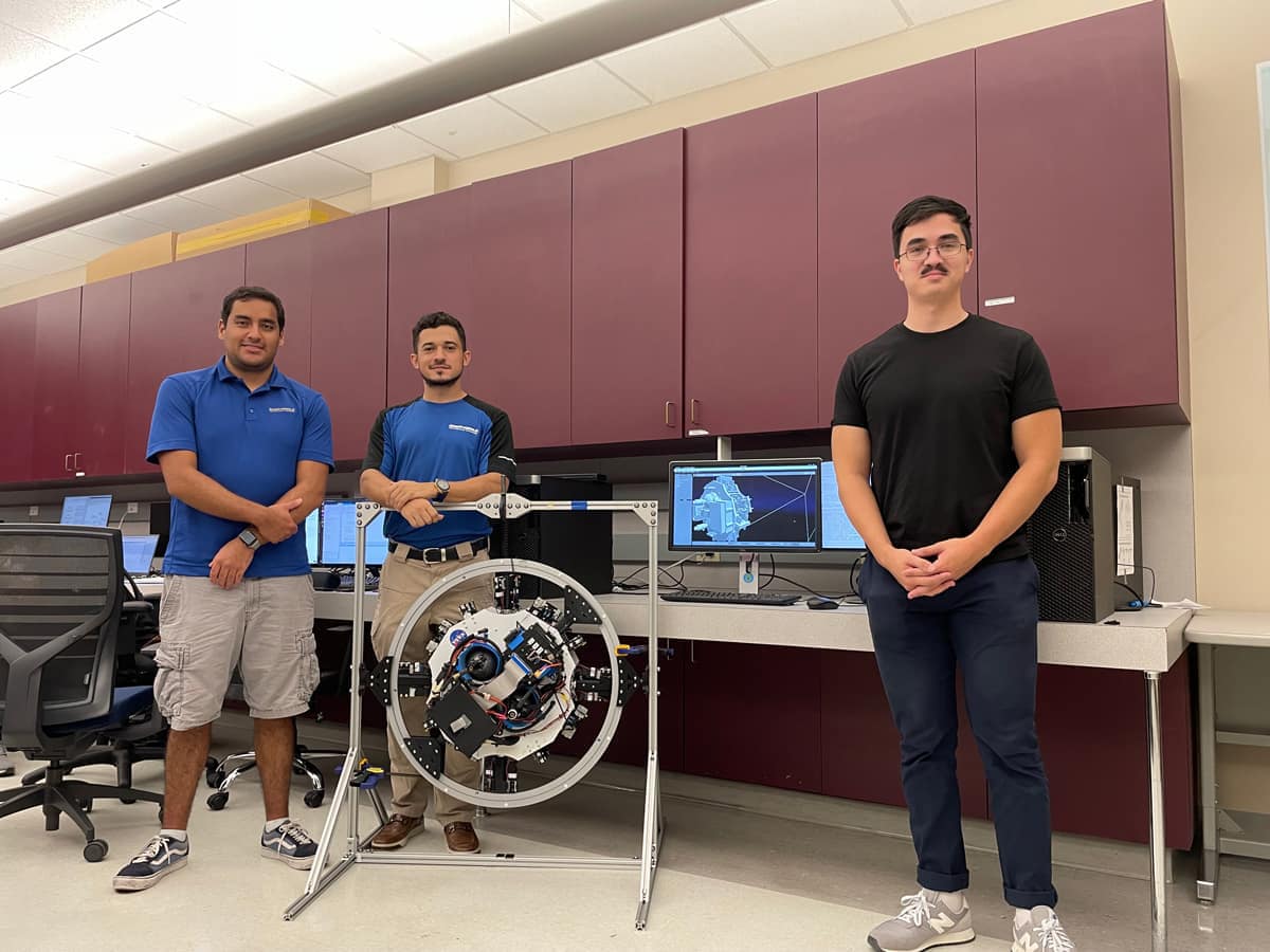Three students stand by a drone