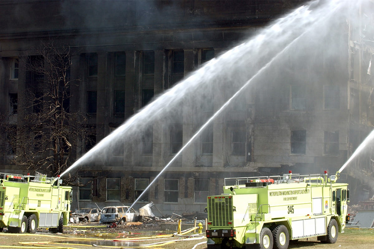 Two fire trucks putting out a fire with water hoses