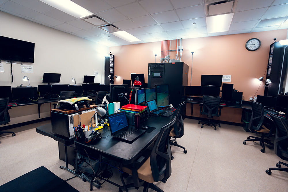 A lab with computers, a TV screen and a server stack.