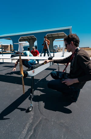 A person crouched down looking a drone.