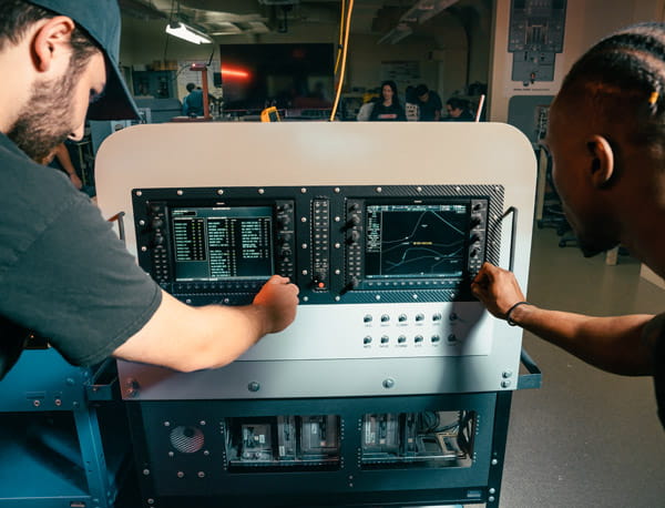 Two people working together on some equipment.