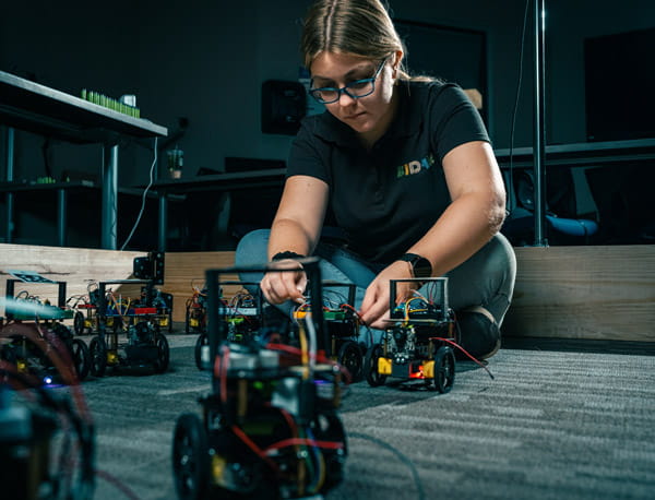 A person sitting on the floow, working on machines.