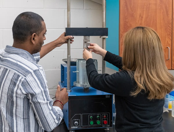 Two people working together on a machine in a laboratory.