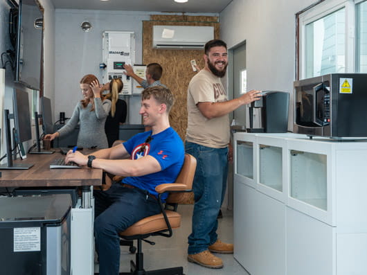 A group of 5 people working on equiment in a laboratory.
