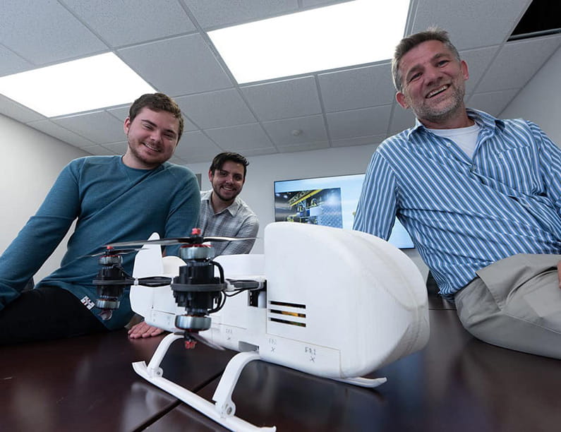 Ph.D. candidate Jackson Asiatico, master’s student Sebastian Lopez and Dr. Michael Kinzel pose with a prototype of the Dragonfly rotorcraft lander