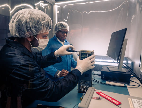 People wearing har nets and safety equipment while working in a laboratory.
