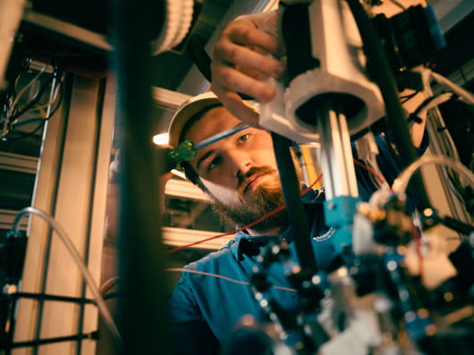 A person wearing safety goggles, working in a laboratory.