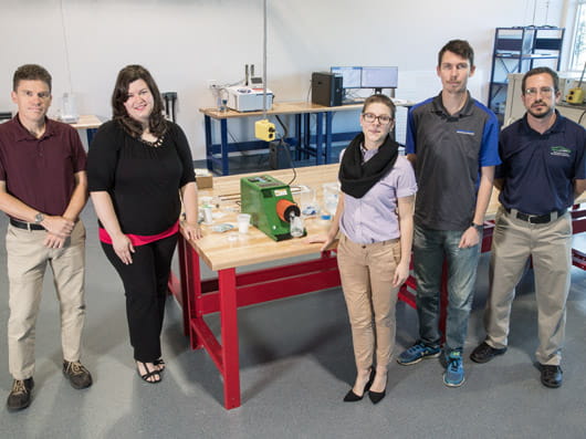 A group of five people standing together in a laboratory.