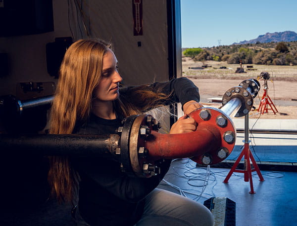 A student tightens bolts on a metal pipe in the Embry-Riddle Propulsion Lab.