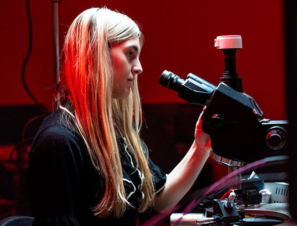 A female Embry-Riddle student looks through a microscope.