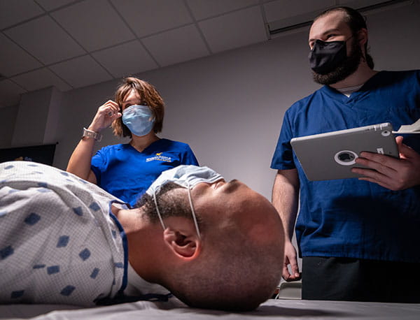 Embry-Riddle students and professors learn around a medical dummy.
