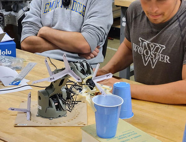 Students perform research with a small device grabbing plastic cups.