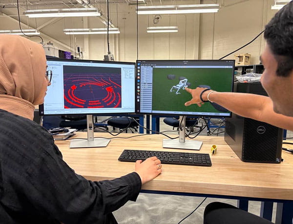 Students point a computer monitor while running a simulator program.