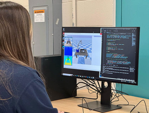 A student works at a computer programming code for a simulation.