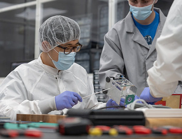 A student in protective equipment screws the frame of a device.