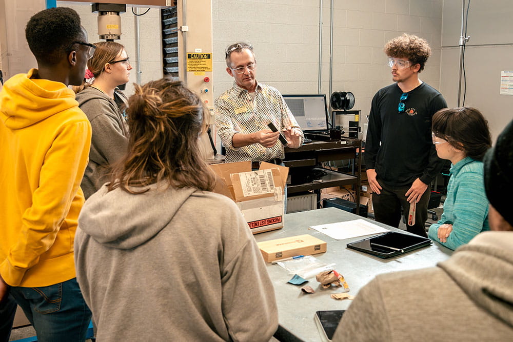 Embry-Riddle students watch a demo from the lab director in the Structural Testing Lab