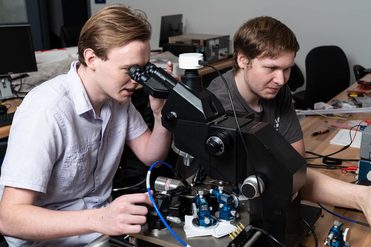 Daniel Sommer and John Sahr working with microscopes and probes to test the power properties of antenna materials