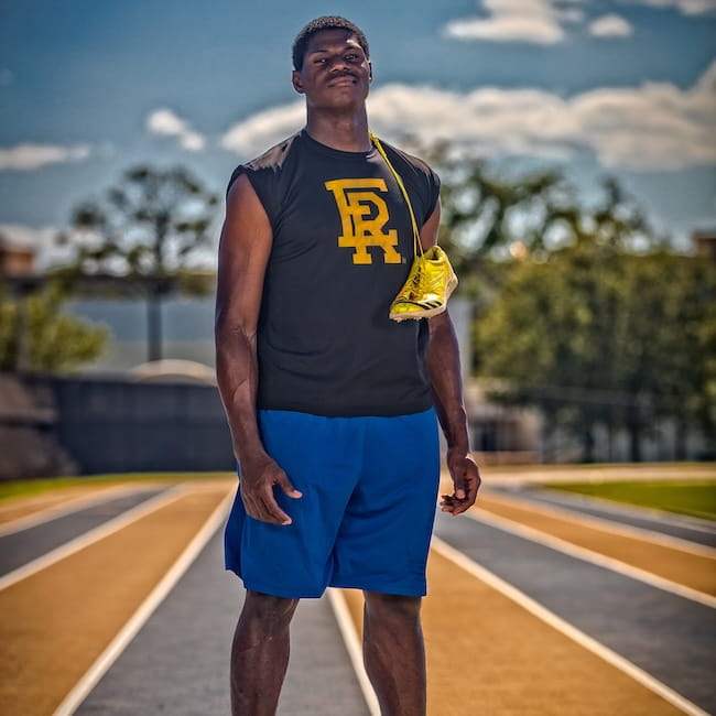 An Embry-Riddle student stands on the track with running shoes tied around his neck